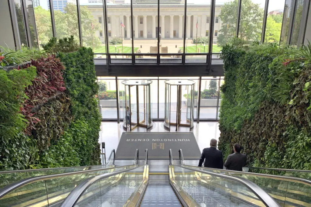 Two large living plant walls flank a trio of escalators in the lobby of a office building.