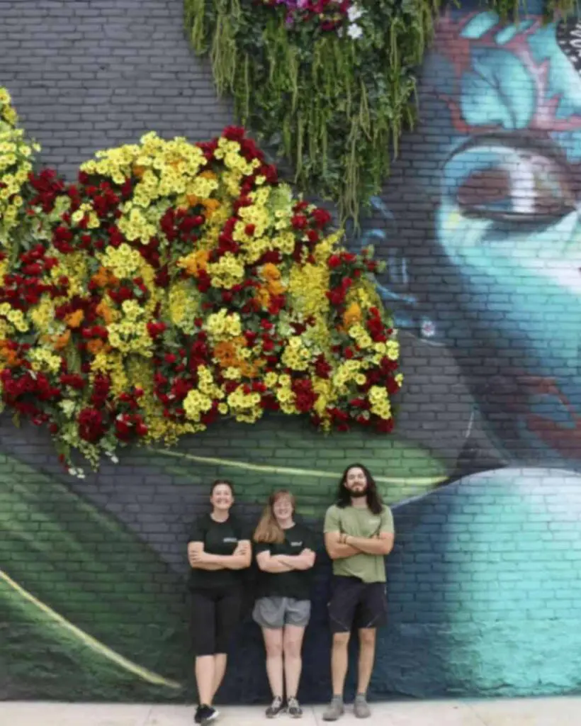 Three People Standing at a Beautifully Decorated Wall
